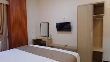 Une chambre d’hôtel comprenant un lit, un bureau, un miroir, une télévision et une armoire.