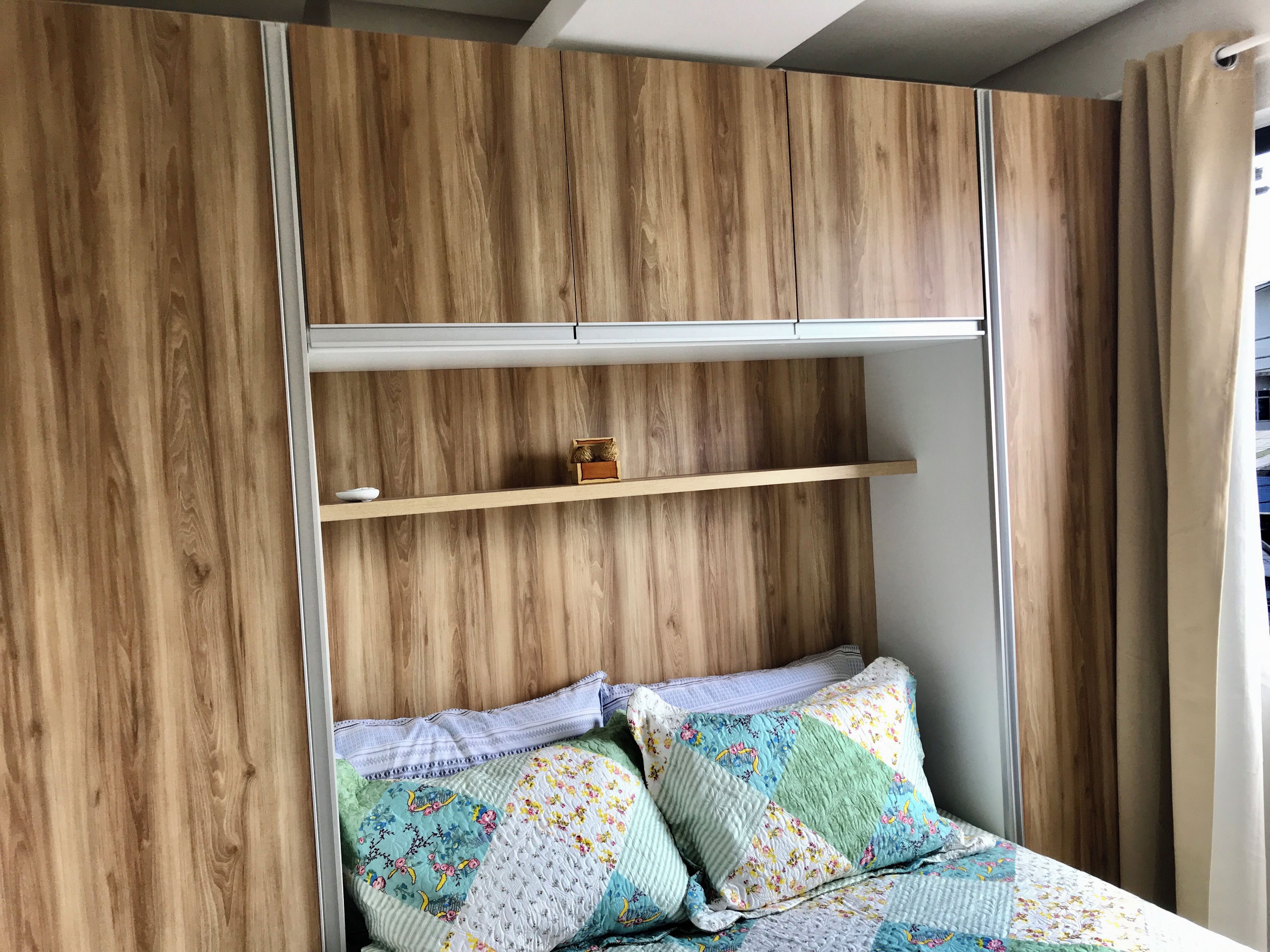 A bedroom with a bed, a wooden wardrobe, and a shelf unit.