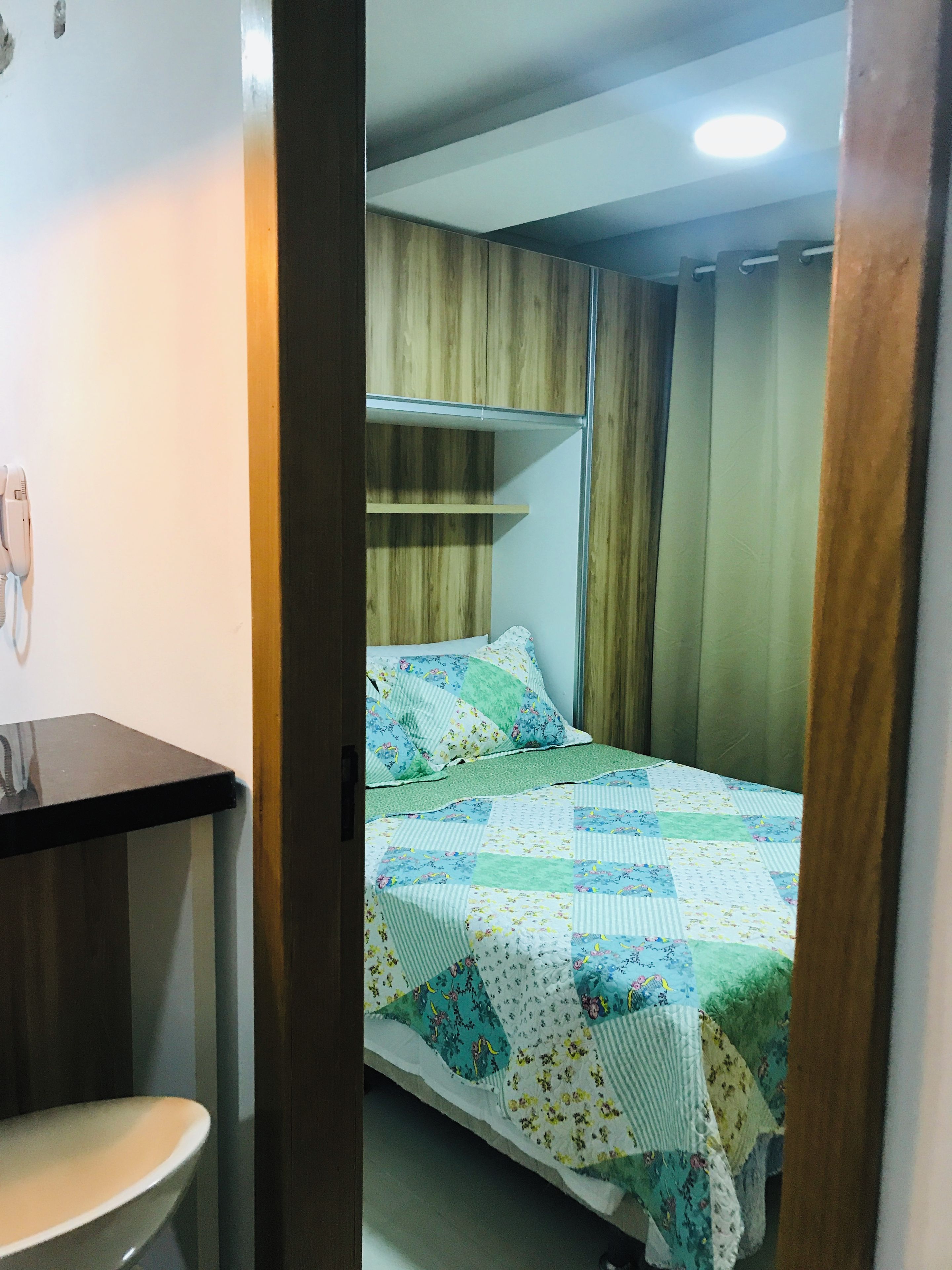 A bedroom with a bed, a bedside table, and a wooden wardrobe.