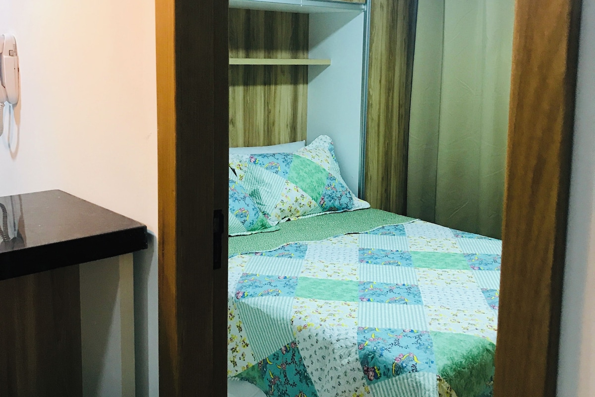 A bedroom with a bed, a bedside table, and a wooden wardrobe.