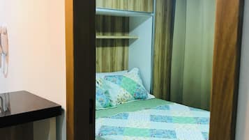 A bedroom with a bed, a bedside table, and a wooden wardrobe.