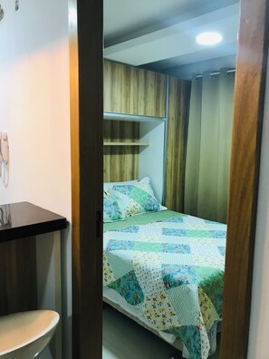 Un dormitorio con cama, mesita de noche y un armario de madera.