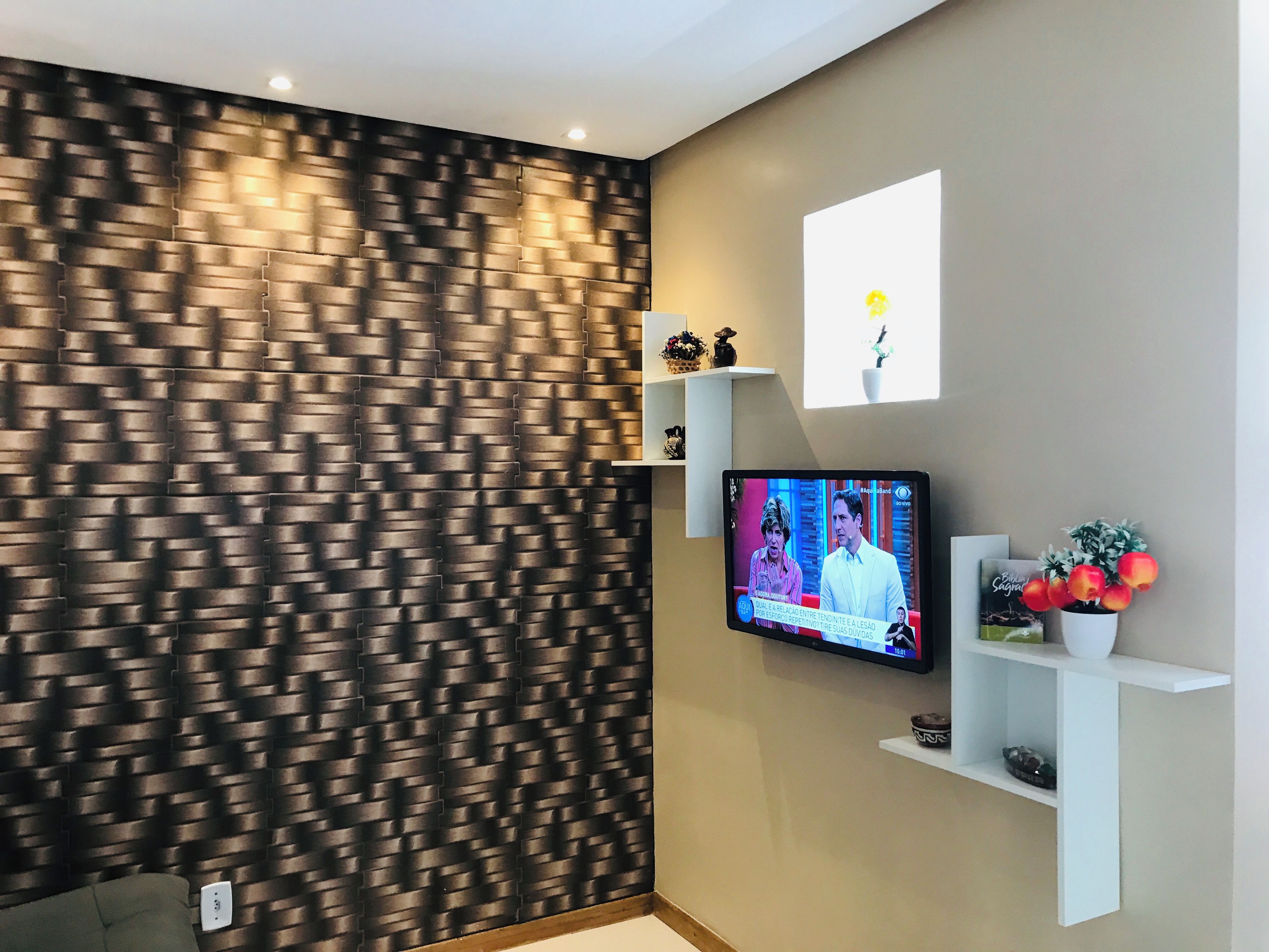 Una sala de estar moderna con una pared texturizada, un televisor de pantalla plana montado en la pared y un estante con objetos decorativos.