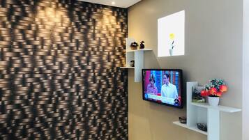 Una sala de estar moderna con una pared texturizada, un televisor de pantalla plana montado en la pared y un estante con objetos decorativos.