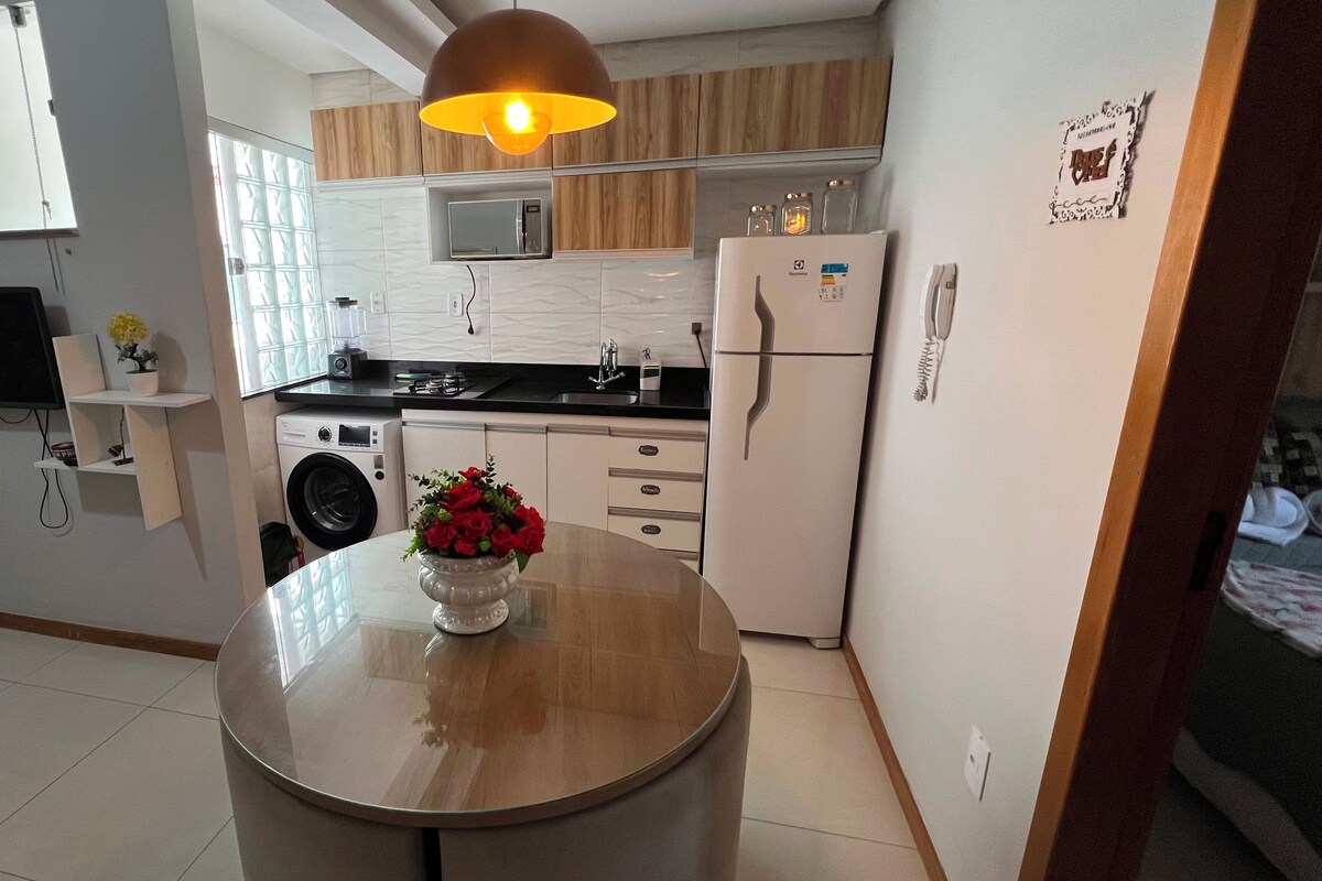 Cocina compacta con lavadora, refrigerador y comedor con mesa.