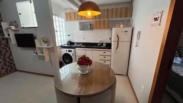 A compact kitchen with a washing machine, a refrigerator, and a dining area with a table.
