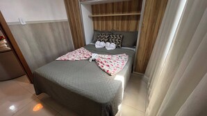 Ein ordentlich bezogenes Bett mit gesteppter Decke, Kissen und einer darüber gefalteten Decke.