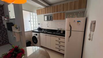 Cocina compacta con microondas, refrigerador, lavamanos y lavadora.