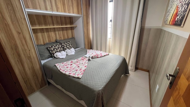 Ein Schlafzimmer mit einem Bett, Kissen, einer Decke, einem Kleiderschrank und einer Tür.