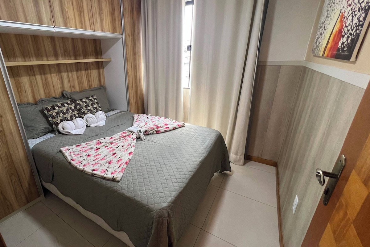 A bedroom with a bed, pillows, a blanket, a wardrobe, and a door.