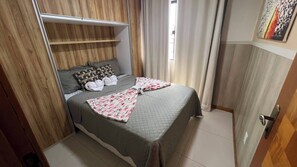 A bedroom with a bed, pillows, a blanket, a wardrobe, and a door. - Apto 201 Flat Prático Perto de Tudo (Belém)