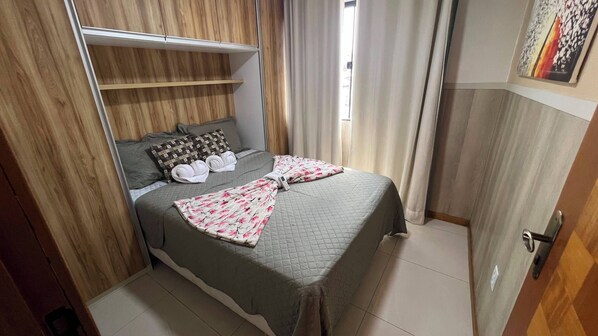 A bedroom with a bed, pillows, a blanket, a wardrobe, and a door. - Apto 201 Flat Prático Perto de Tudo (Belém)