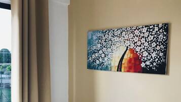 Habitación de hotel con cama, ventana con cortinas y un cuadro colgado en la pared.
