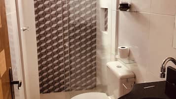 A bathroom with a toilet, sink, and shower area.