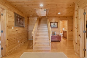 Ein Holzinnenraum mit einer zentralen Treppe, Holzwänden und einem gerahmten Bild auf der linken Seite.