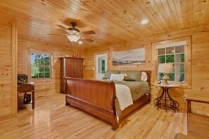 A wooden-paneled bedroom with a bed, a ceiling fan, a painting, and a window. - New listing! Cabin with mountain view-fire pit-hot tub-privacy-8 min to ASU (Boone)
