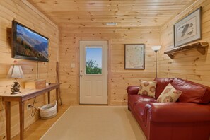 A cozy room with a wooden interior, a leather sofa, a television, and a map on the wall. - New listing! Cabin with mountain view-fire pit-hot tub-privacy-8 min to ASU (Boone)