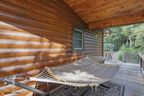 Eine Holzhütte mit einer Hängematte und einer Holzterrasse.