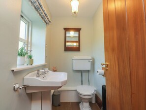 A small bathroom with a white sink, a toilet, and a mirror above the toilet. - The Shippon (Ormskirk)