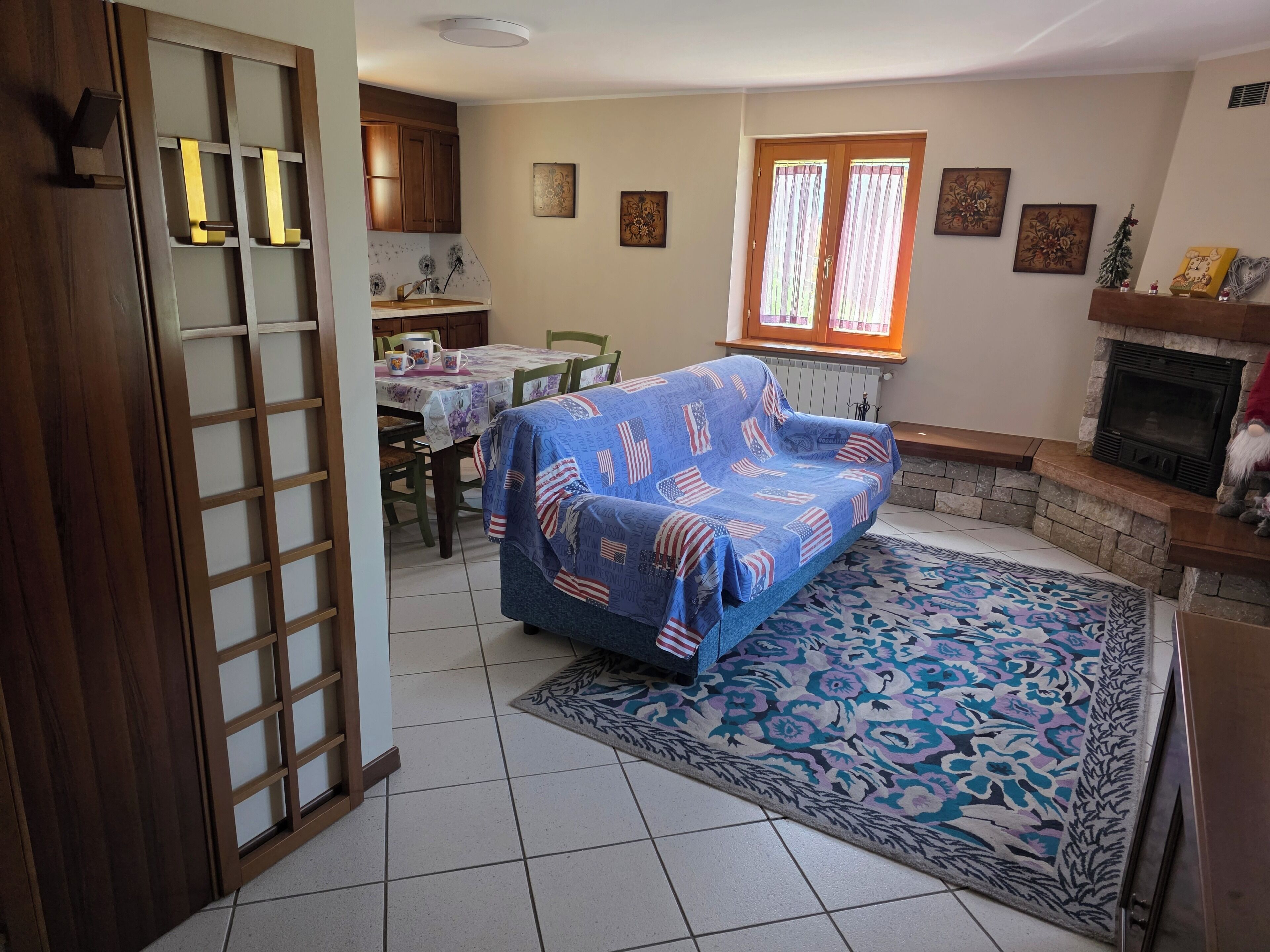 A living room with a sofa, dining table, chairs, a fireplace, and a window with curtains.