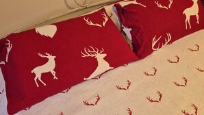 A bed with a white headboard, a red and white patterned bedspread, and a white pillow with a red and white design. - House with garden and garage near the slopes (San Pietro)