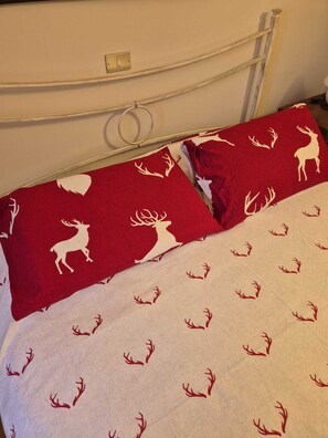 A bed with a white headboard, a red and white patterned bedspread, and a white pillow with a red and white design. - House with garden and garage near the slopes (San Pietro)