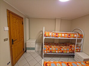 A room with a bunk bed, a wooden door, a small dresser, and a light switch. - House with garden and garage near the slopes (San Pietro)