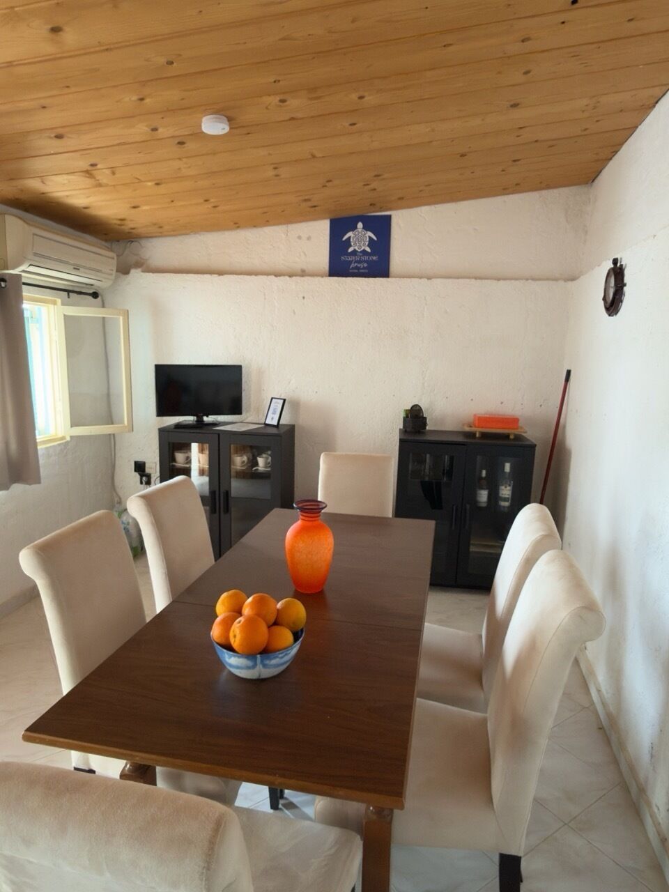 Ein Essbereich mit einem Holztisch, Stühlen und einer Schüssel Orangen.