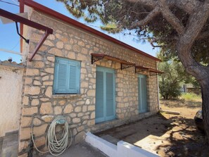 A stone building with two windows and a covered outdoor area. - A stone retreat 40m from the sea, in a private 1,200m² estate on Aegina island. (Aegina)