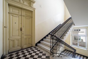A staircase with a checkered floor leading to a landing with double doors. - Apartamenty Sun & Snow Smolna (Warszawa)