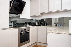 Una cocina moderna con armarios blancos, electrodomésticos de acero inoxidable y encimera de granito.