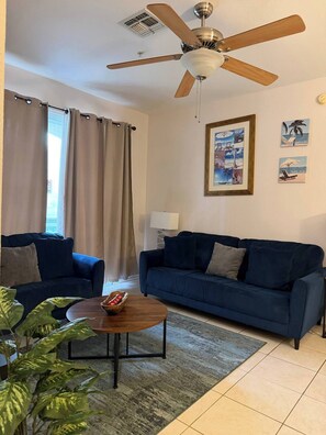 A living room with a ceiling fan, two sofas, a coffee table, and a lamp. - Windsor Palms apartment near Disney (Kissimmee)