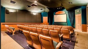 Ein Theater mit Sitzreihen, einer Leinwand und einem Projektor.