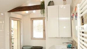Une salle de bain avec une baignoire blanche, un lavabo, un miroir et une fenêtre.