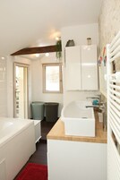 Un baño con una bañera blanca, un lavabo, un espejo y una ventana.