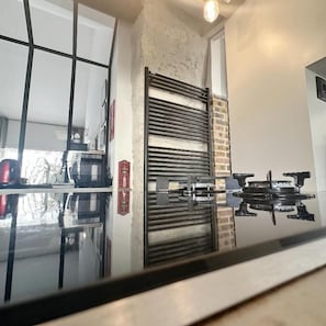 Una cocina con encimera de vidrio, un estante de metal y una pared de ladrillo.