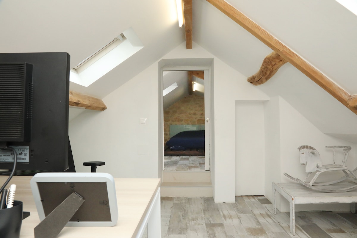 Ein Schlafzimmer im Dachgeschoss mit schrägverdeckter Decke, einem Bett, einem Schreibtisch mit Computer und einem Stuhl.