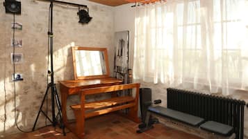A room with a wooden desk, a mirror, a radiator, and a window with sheer curtains.
