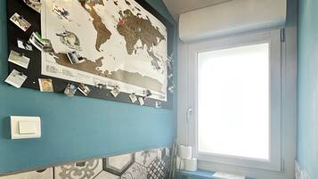 Baño con inodoro, mapa en la pared y ventana.
