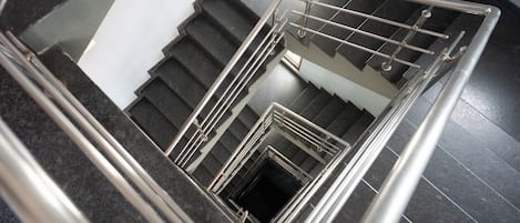 A staircase with a metal handrail and black steps.