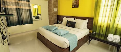 Habitación de hotel con cama, mesita de noche, aire acondicionado, espejo y ventana con cortinas.