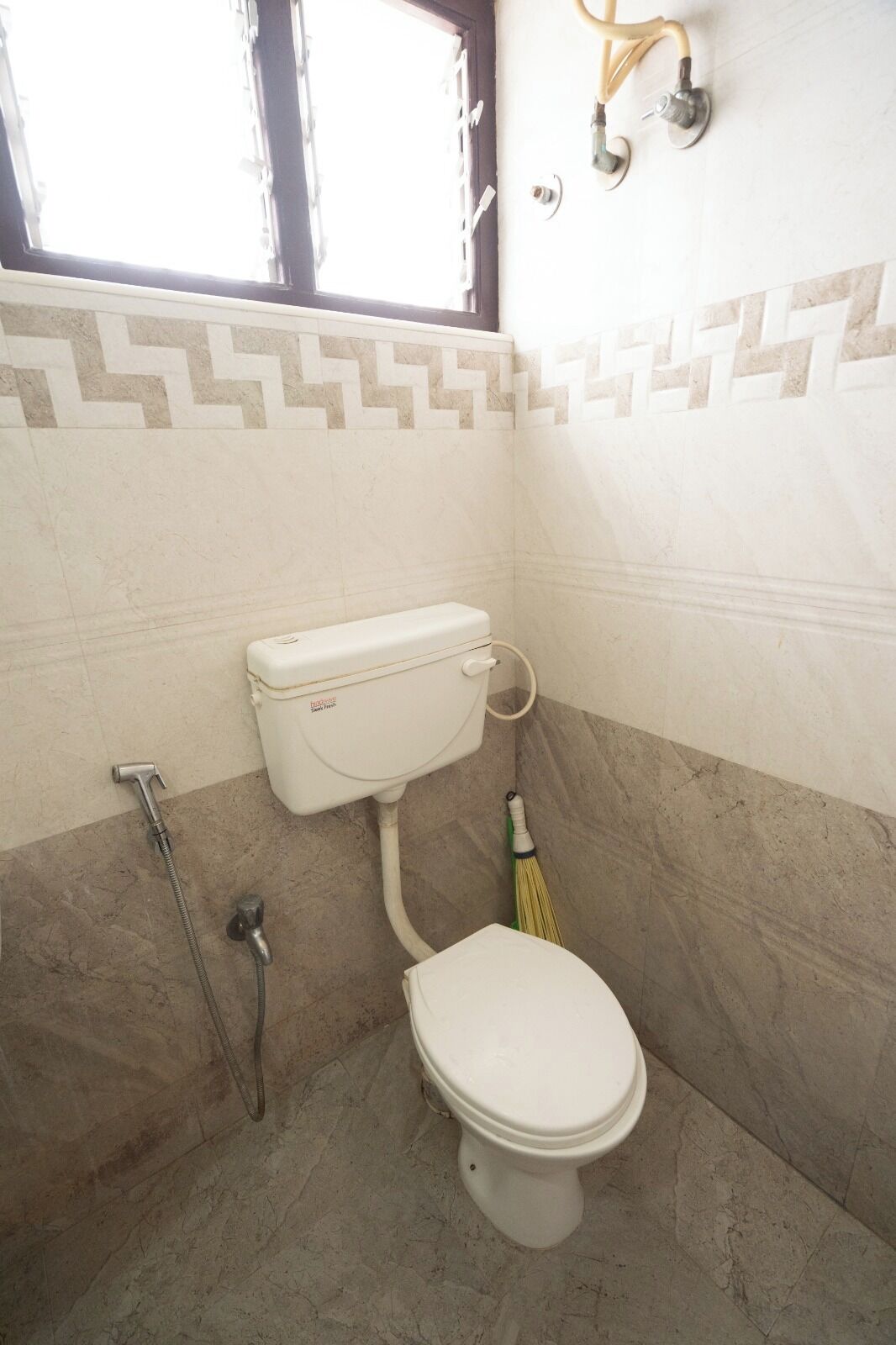 A bathroom with a toilet, a shower, and a window.
