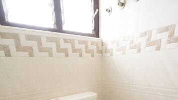 A bathroom with a toilet, a shower, and a window.