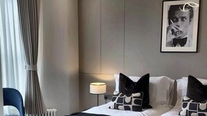 A modern hotel room with a double bed, a side table, a lamp, and a framed picture on the wall. - Luxury 8 Bed House, Games Room & Free Parking (Bedford)