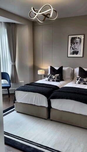 Ein modernes Hotelzimmer mit einem Doppelbett, einem Nachttisch, einer Lampe und einem gerahmten Bild an der Wand.