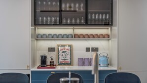 A kitchen with a marble countertop, a coffee machine, a kettle, and a framed picture. - Luxury 8 Bed House, Games Room & Free Parking (Bedford)