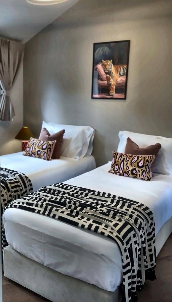 A hotel room with two beds, each with patterned pillows and a striped blanket. - Luxury 8 Bed House, Games Room & Free Parking (Bedford)