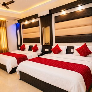 Quarto de hotel com duas camas, cada uma com roupa de cama vermelha e branca, um espelho grande e um ventilador de teto.