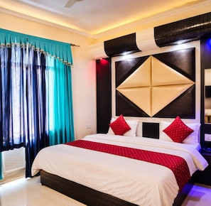 Una habitación de hotel con una cama grande, un cabecero moderno y un ventanal con cortinas.
