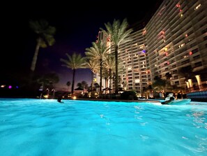 A nighttime view of a hotel pool area with a large building in the background. - 3BR 3BA Beachfront 8PPL.Most gorgeous resort- 3rd floor unit and 3rd floor parkg (Panama City Beach)